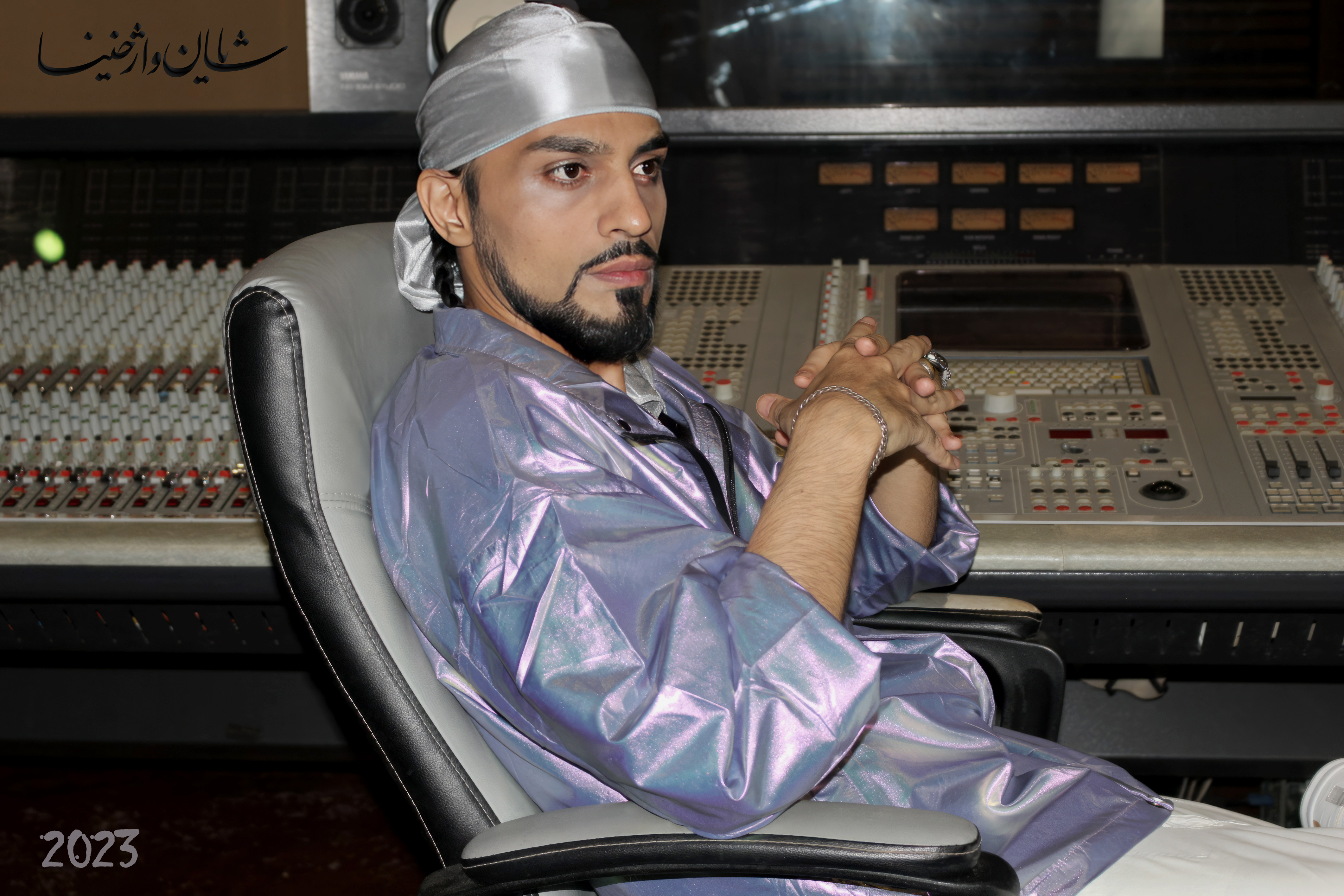 شایان در استودیو ضبط با لباس براق نشسته پشت کنسول میکس