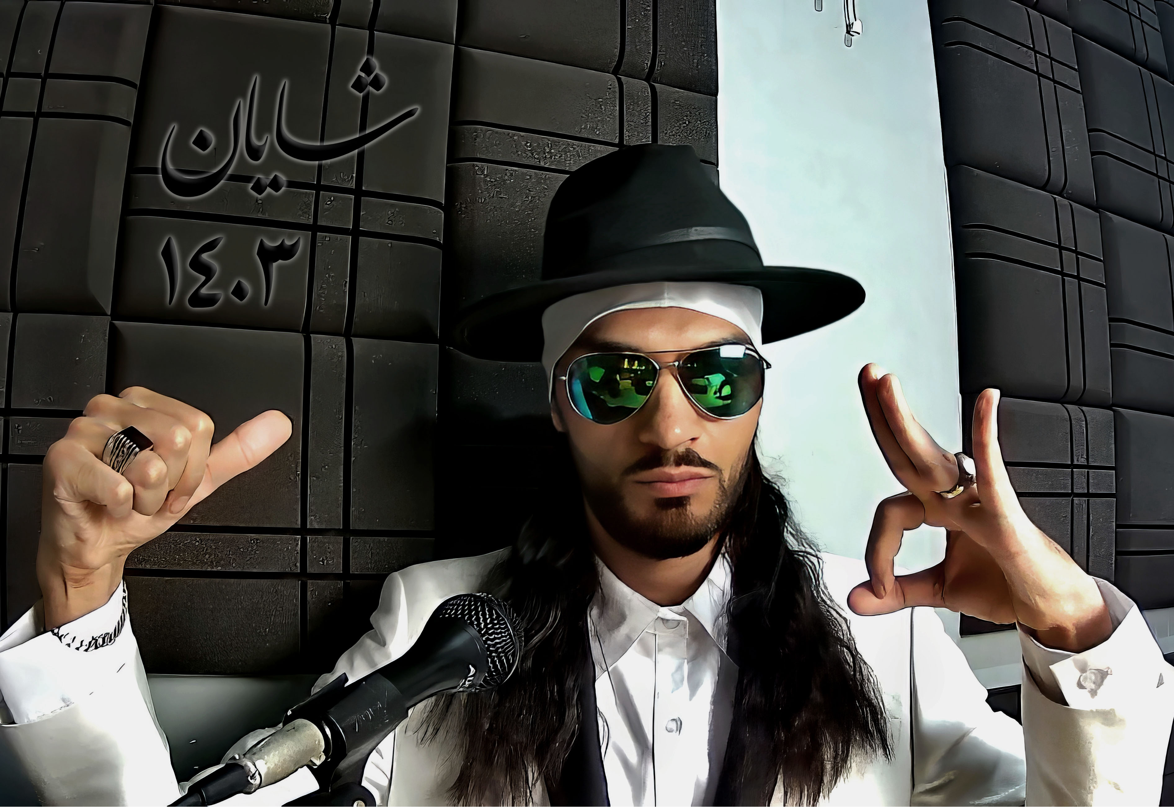 شایان واژخنیا با کلاه سیاه و عینک آفتابی در حال دادن علامت دست
